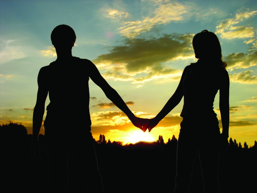 Loving couple holdind on the hands and sunset